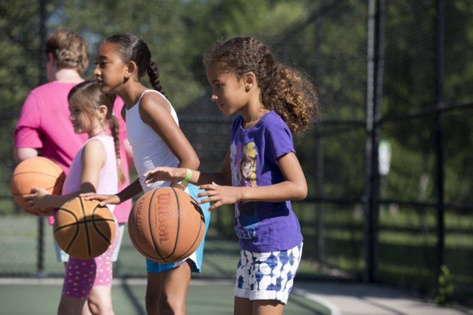 Girls lined up with basketballs at outdoor court