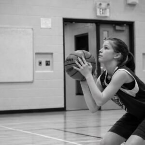 A young player in a Shake True Hoops gym setting her hands on the ball and focusing on the rim before she shoots