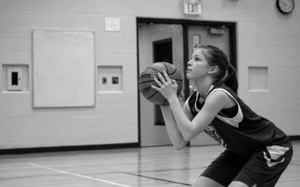 A young player in a Shake True Hoops gym setting her hands on the ball and focusing on the rim before she shoots