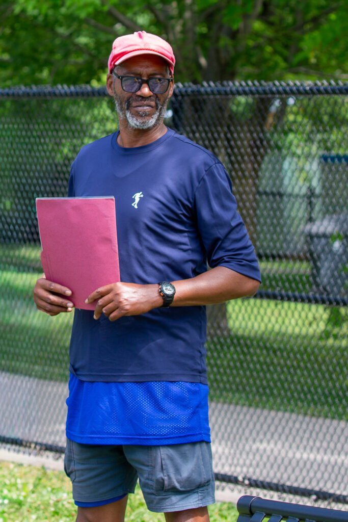 Steve Shaker Cuevas holding a clipboard at the outdoor basketball court